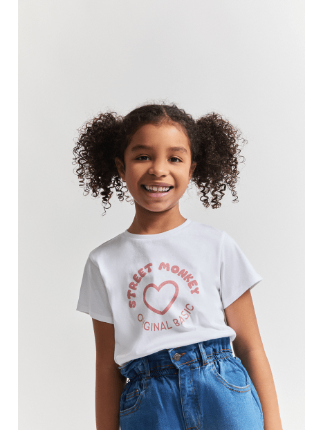 Niña sonriente en blusa blanca Street Monkey con corazón y frase 'Original Basic' en Kinder Guatemala.