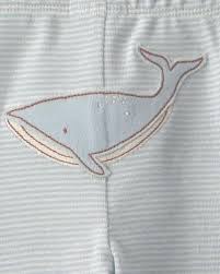 Primer plano del pantalón azul de bebé Carter's con un aplique de ballena azul y contorno café.