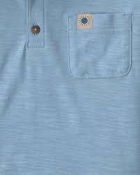 Detalle del polo azul claro Carter's para niño con cuello, botones de madera y bolsillo con parche.