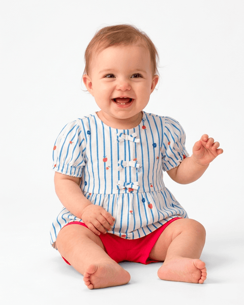 Bebé sonriente vistiendo conjunto Carter's, blusa de rayas con motitas y short rojo.