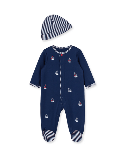 Pijama con pies azul marino Little Me para bebé niño con estampado de barcos y gorro a rayas a juego.