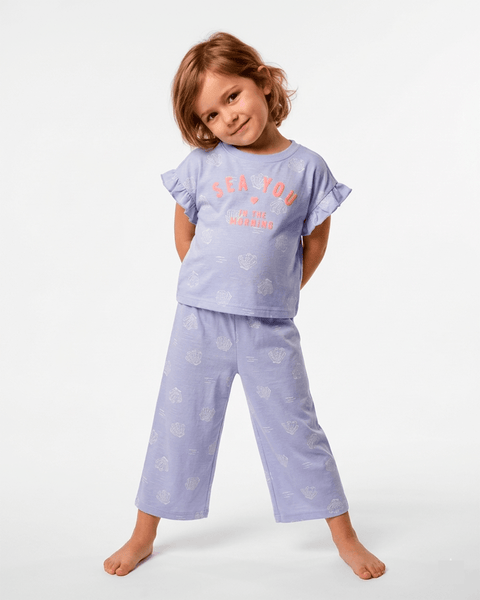 Niña feliz vistiendo pijama Carter's lila con estampado de conchitas y frase "Sea You".