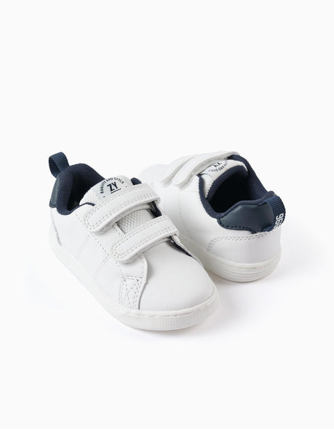 Tenis Zippy 1996 blancos para niños con velcro y detalles azul oscuro sobre fondo blanco.