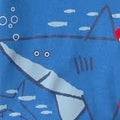 Primer plano de camiseta de pijama azul claro con diseño de tiburón grande y peces pequeños.