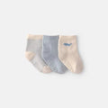 Pack de 3 calcetines escarpines Carter's para bebé: azul liso, rayas y beige con ballena.